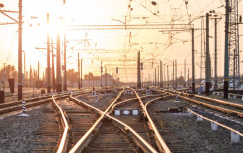 An empty railway sorting station or terminal with lots of junction, crossroads, semaphore showing red or green light, in a bright sunset light. The difficulty of finding the right way concept